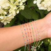 Wrist with colorful gold filled chains against a background of green foliage